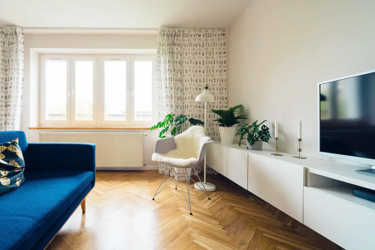 Sala com soalho em espinha, janela larga e móvel baixo branco